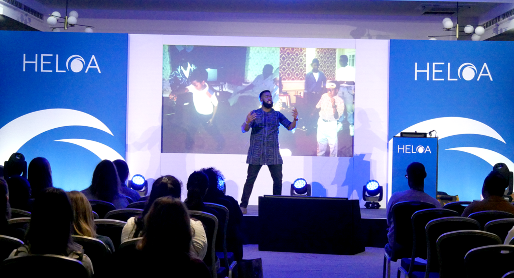 An image of Alim Kamara on stage with open arms, and pictures of his childhood on the screen behind him